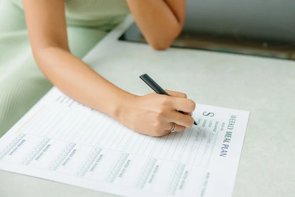 Person planning a weekly meal schedule on paper